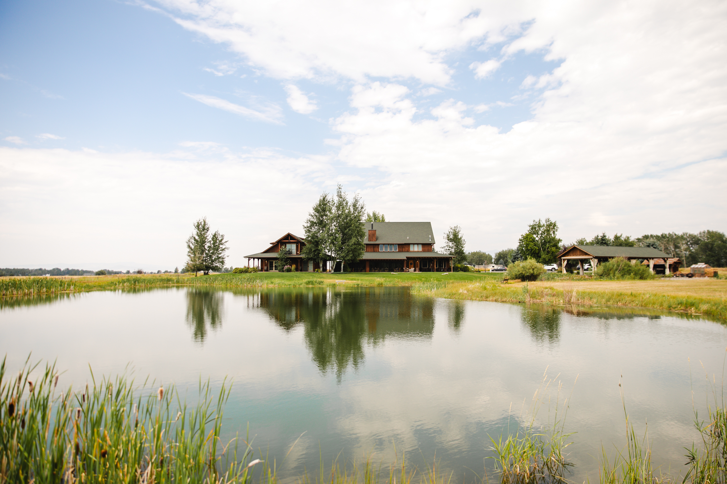 grl0824 7 Rustic house by a pond with trees and sky.