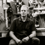 Man sitting in workshop with tools on wall