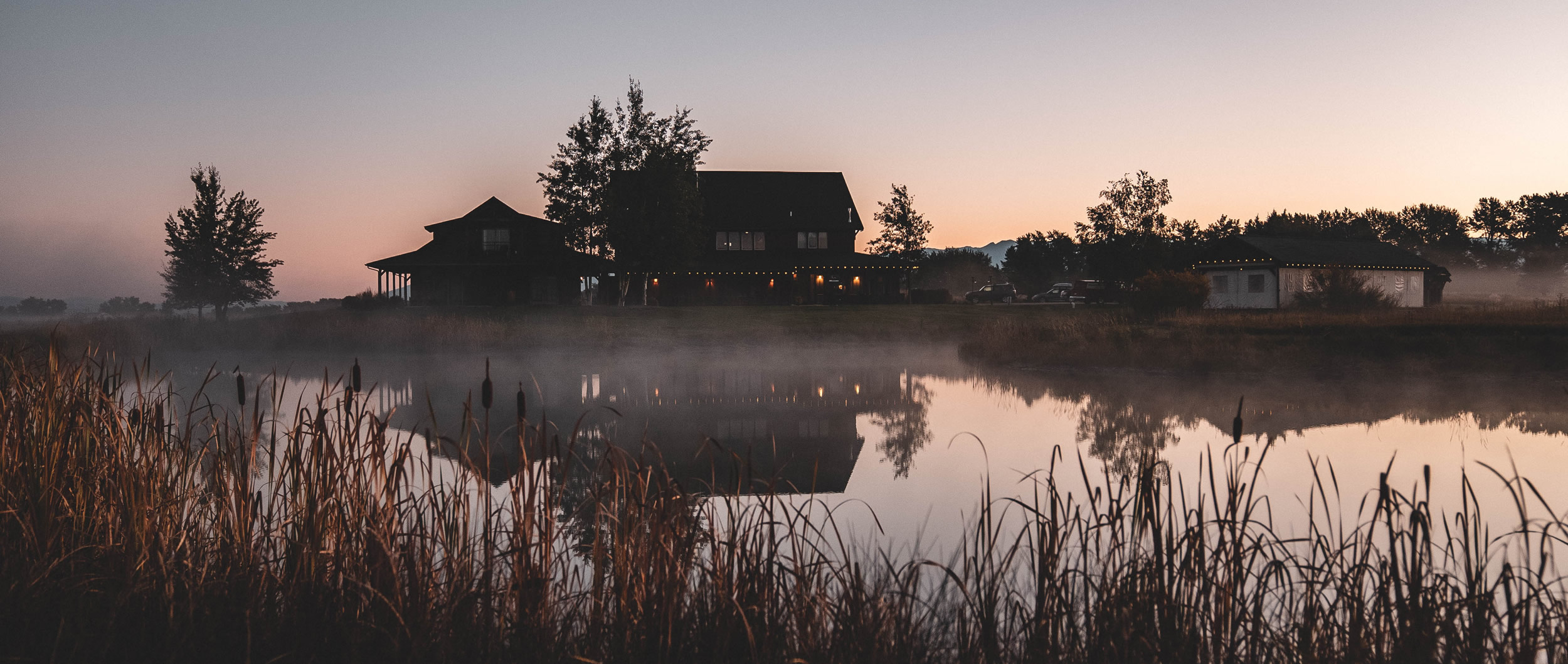 Rustic house by lake at dusk with reflections.