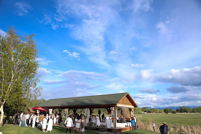 Outdoor wedding reception under pavilion with blue sky