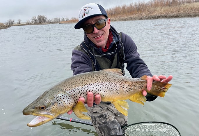 Man holding large fish by the river.