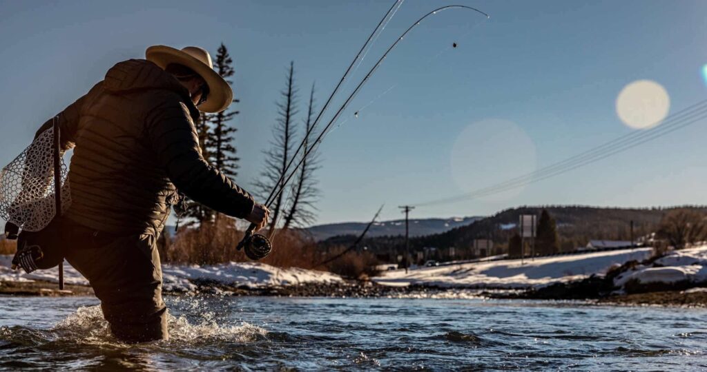 Person fly fishing in snowy mountain river